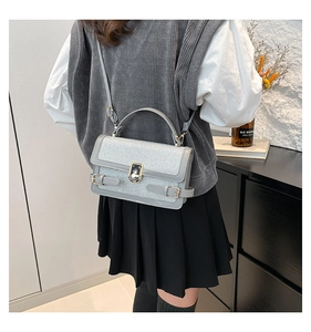 Detail of grey sequin crossbody bag with metal twist lock and adjustable shoulder strap