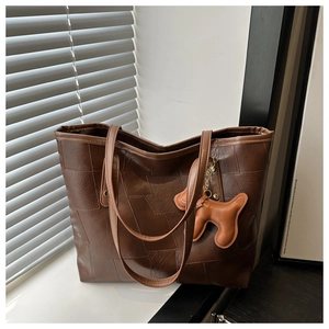 Detail of a brown patchwork leather tote bag with a cute dog pendant in a cozy window setting