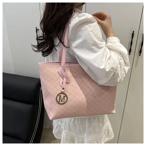Detailed close-up of pink monogram tote bag with gold M pendant and textured finish