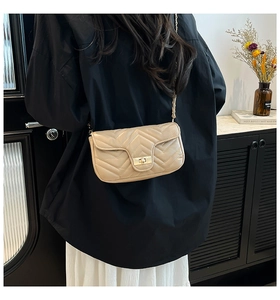 Détail d'un sac bandoulière matelassé beige avec coutures en V et fermoir doré