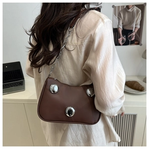 Detail of coffee brown crossbody bag with silver metal studs and chain strap on model