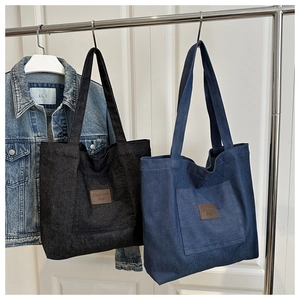 Gros plan de sacs cabas en denim gris et bleu avec détail de l'écusson en cuir Fashion Bag