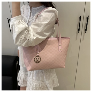 Close-up of pink tote bag featuring M monogram print and metallic logo charm detail