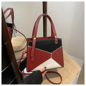 Close-up of geometric color-block handbag with contrast stitching and gold metal rings
