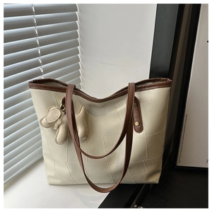 Detailed view of beige tote bag with brown straps and cute animal charm on a window sill