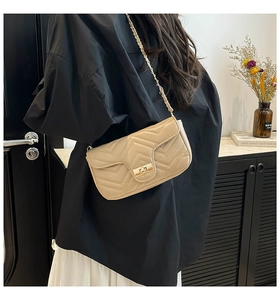 Détail du sac beige matelassé avec bandoulière chaîne dorée et fermoir pivotant en métal