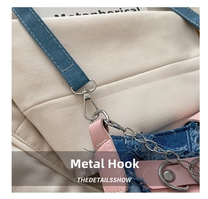 Gros plan du crochet mousqueton en métal argenté et chaîne sur sac en denim