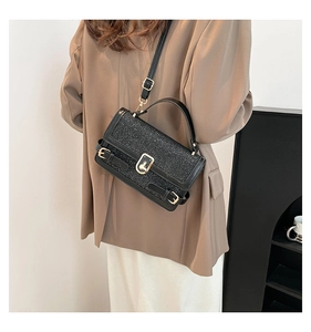 Detailed view of black glitter crossbody bag with gold buckle and adjustable strap