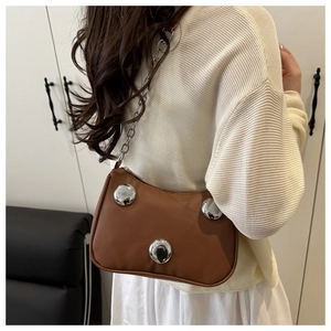 Detail of a brown leather crescent bag with silver rivet studs and metal chain strap