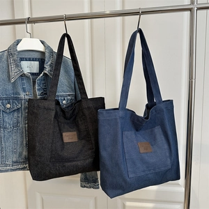 Minimalist canvas tote bag with outer pocket and leather patch in black and blue