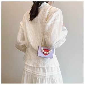 Detailed back view of a lavender crossbody bag with red heart and pearl embellishments