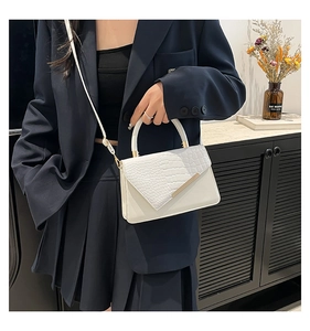 Dettaglio della borsa bianca motivo coccodrillo con fibbia dorata su blazer blu scuro