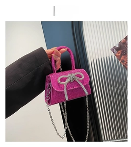 Detail of rose red glitter bag featuring a sparkling silver rhinestone bow and chain