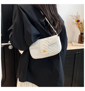 Détail du sac matelassé blanc avec fermoir doré et bandoulière chaîne en cuir