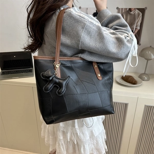 Minimalist black patchwork tote bag with brown straps and cute dog charm for commuting