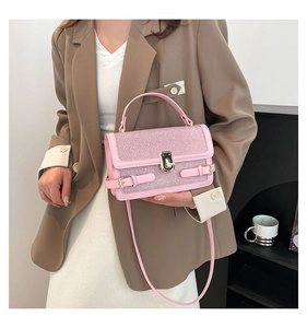 Detail of pink sequin shoulder bag with golden buckle held by a model in a brown suit