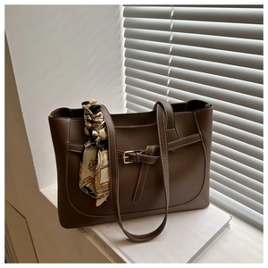 Détail d'un sac cabas en cuir marron avec surpiqûres blanches et foulard en soie décoratif