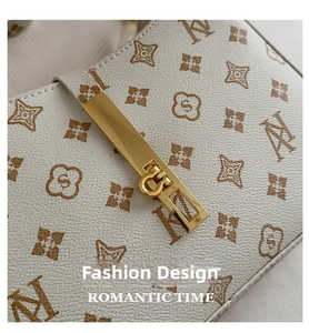Close-up of golden metal clasp on beige monogram leather shoulder bag with chain strap