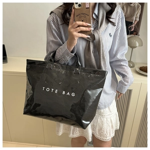 Detailed view of large black shiny tote bag with white TOTE BAG lettering text