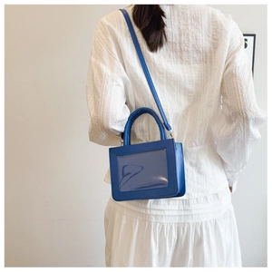 Detail of dark blue PVC shoulder bag with clear window shown on model for size and fit