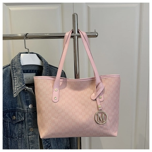 Detail of pink tote bag with monogram M pattern and golden circular metal pendant