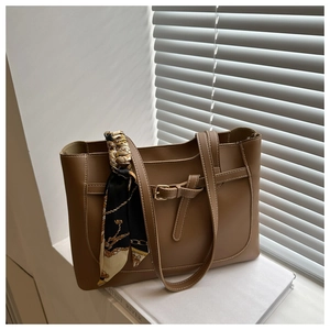 Détail du sac cabas en cuir marron avec boucle décorative et accessoire foulard en soie