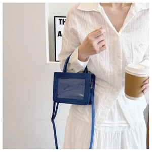 Detail of dark blue mini crossbody bag featuring a clear PVC window and leather texture