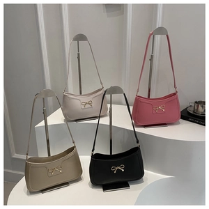 Four minimalist faux leather baguette bags with gold bow hardware in a tiered display