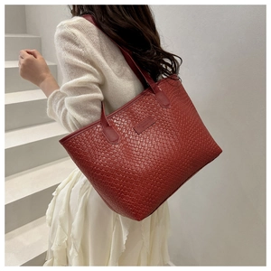 Detail shot of a deep red woven texture tote bag featuring brand tag on white stairs