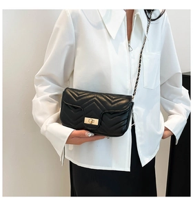Détail d'un sac à bandoulière en cuir noir matelassé avec motif chevron et boucle dorée