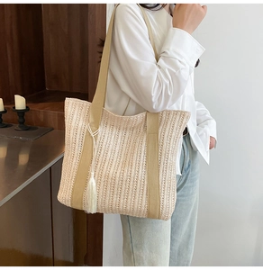 Dettaglio della borsa tote in paglia intrecciata con spalline in tela e nappa bianca