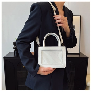 Sac à main en cuir blanc avec fenêtre transparente et boucles dorées porté par modèle