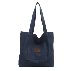 Classic dark blue denim tote bag with a front pocket and stylish brown leather logo patch