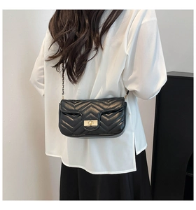 Détail du sac bandoulière noir matelassé avec fermoir doré et chaîne sur un mannequin
