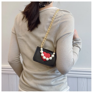 Vue arrière du mannequin portant un mini sac cœur avec perle et chaîne dorée