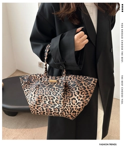 Detailed view of the leopard print tote bag with double handles and metal hardware accents