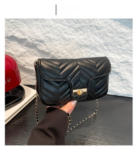 Détail du sac à bandoulière matelassé noir avec fermoir doré et bandoulière chaîne