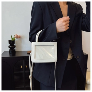 Detail of a white leather mini bag with transparent PVC window held by a model