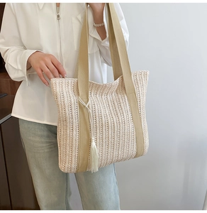 Dettaglio di una borsa tote intrecciata beige con cinturini marroni e nappa a frange