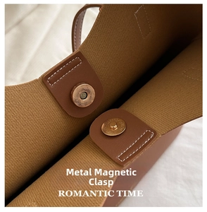 Detail of light gold magnetic snap closures on a khaki brown tote bag's interior