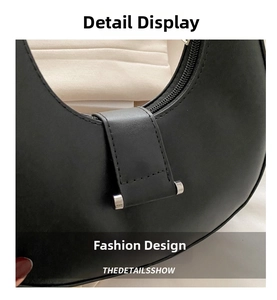 Close-up of black crescent hobo bag with smooth faux leather texture and metal buckle