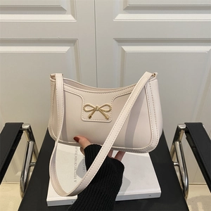 Off-white leather baguette bag with a premium golden metal bow clasp detail