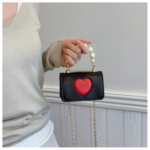 Detail of mini black bag featuring red heart, pearl handle, and gold chain strap