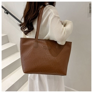 Detailed view of brown tote bag with woven leather texture and embossed logo patch
