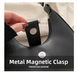 Detail shot of the secure silver magnetic hardware clasp on a black leather crescent bag