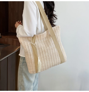 Dettaglio di borsa a spalla in paglia con spalline in tessuto kaki e nappa decorativa