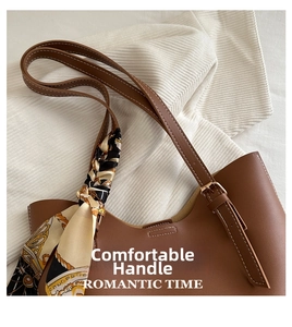 Detail of brown leather tote bag with printed silk scarf and adjustable strap buckle