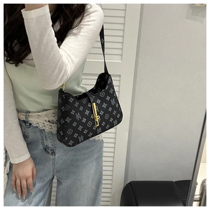 Detail of black monogram shoulder bag with gold metal buckle and leather strap on model