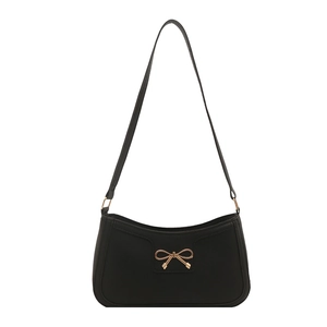 Elegant black crescent shoulder bag with a gold bow buckle and minimalist strap