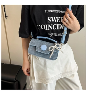 Détail du petit sac carré en denim bleu clair avec boucle ronde et charm en perles